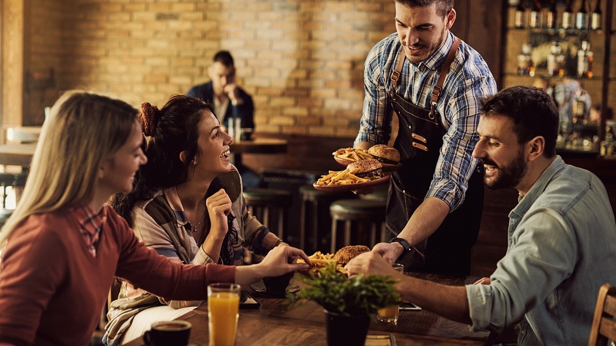 Camarero de mesa atendiendo comensales.
