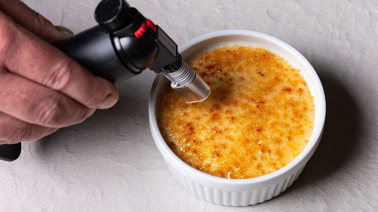 Chef preparando Crème Brûlée de naranja en platillo individual.