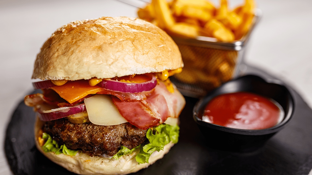 Hamburguesa servida con papas fritas y ketchup.