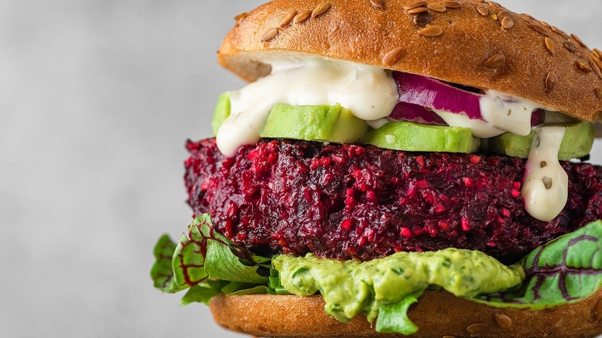 Hamburguesa vegana con mayonesa vegana sobre plato.